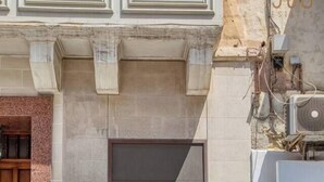 A building with a wooden door, a small window, and a green sign on the wall. - Sliema Central 1BR Apt | Own Entrance, Walk to Sea (Tas-Sliema)