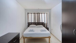 A small, neatly arranged bedroom with a single bed, a bedside table, and a wardrobe. - Sliema Central 1BR Apt | Own Entrance, Walk to Sea (Tas-Sliema)