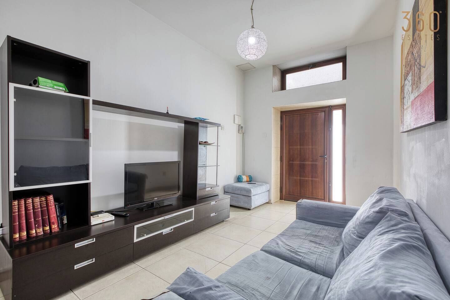A modern living room with a flat-screen TV, a sofa, a coffee table, and a bookshelf.