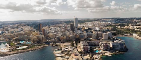 Una vista aerea di una città costiera con un grattacielo importante, un porto turistico e una zona spiaggia.