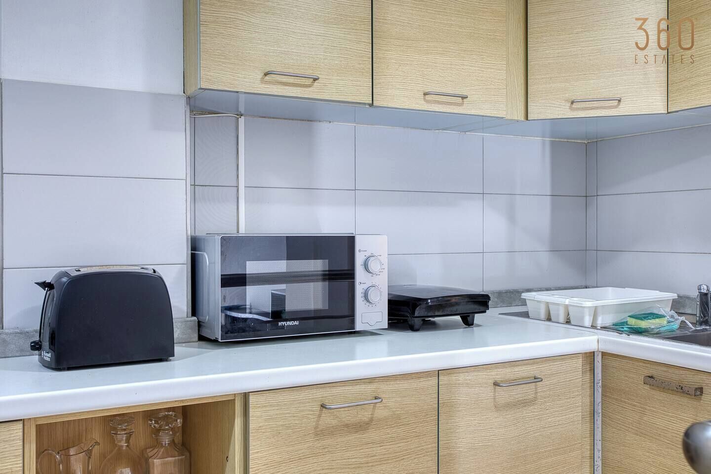 A kitchen with a microwave, toaster, and wooden cabinets.