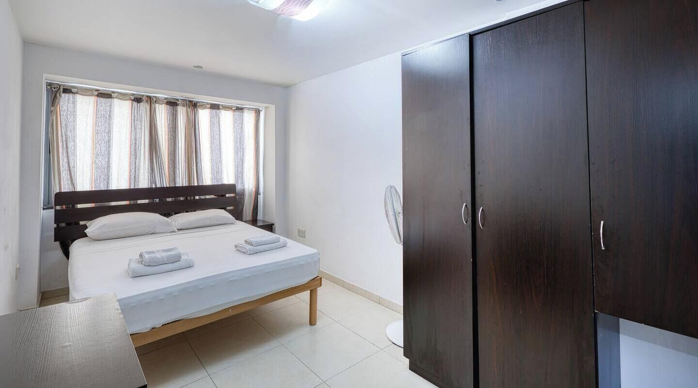 A bedroom with a bed, a wardrobe, and a window with curtains.