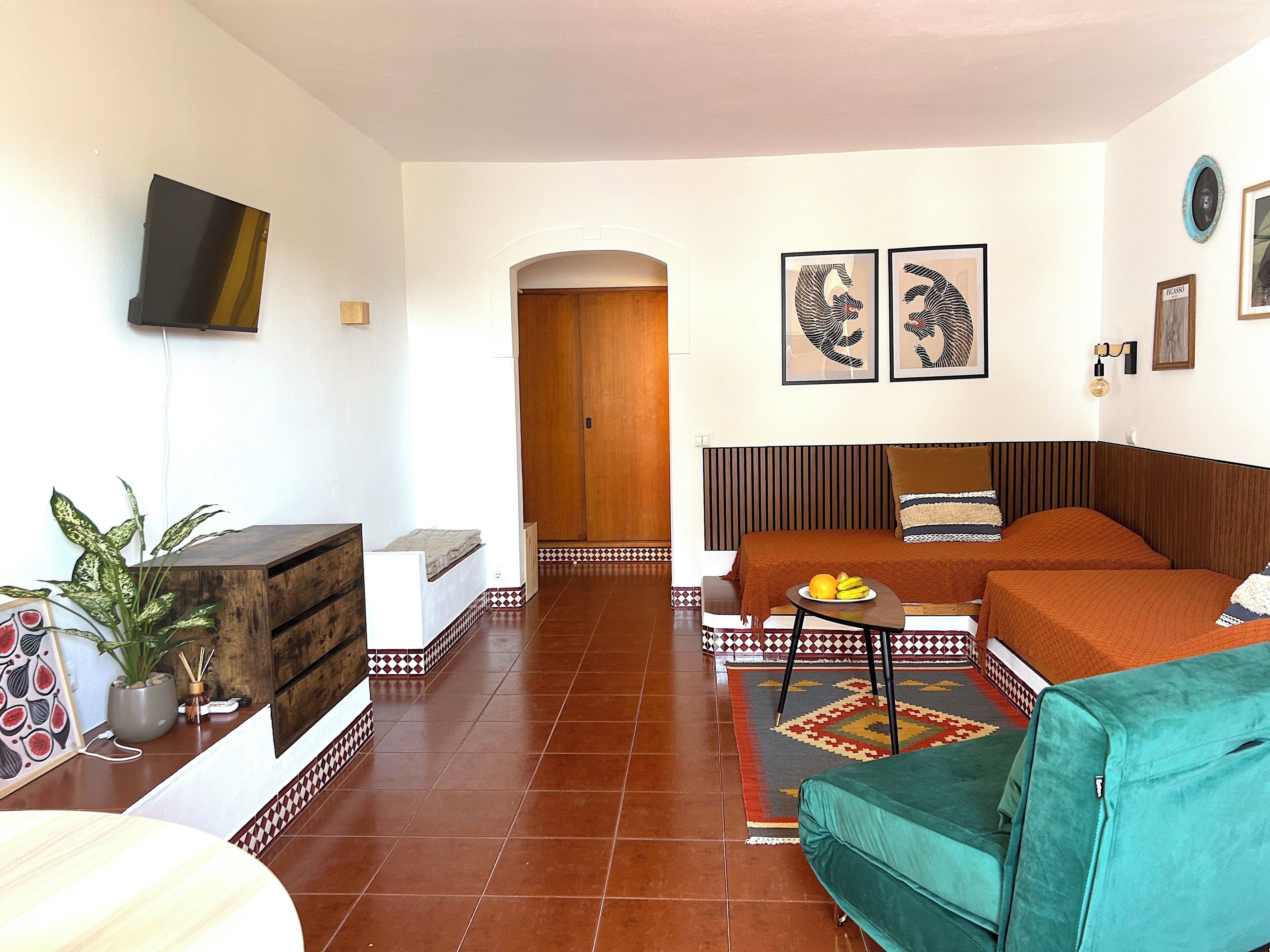 A hotel room with a bed, a sofa, a TV, and a dining table.
