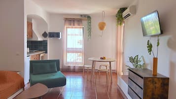 A compact living space with a sofa, a dining table, and a TV mounted on the wall.