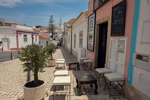Eine Kopfsteinpflasterstraße mit Außenbestuhlung, ein Café und eine Kirche im Hintergrund.