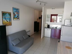 A compact living space with a sofa, a kitchenette, and a dining area. - CALVI 2-bedroom apartment with a garden (Calvi)