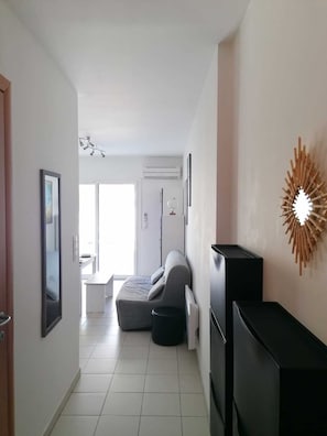 A modern living room with a sofa, a TV, and a decorative wall piece. - CALVI 2-bedroom apartment with a garden (Calvi)