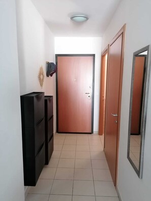 A hallway with a closed door, a wardrobe, and a mirror on the wall. - CALVI 2-bedroom apartment with a garden (Calvi)