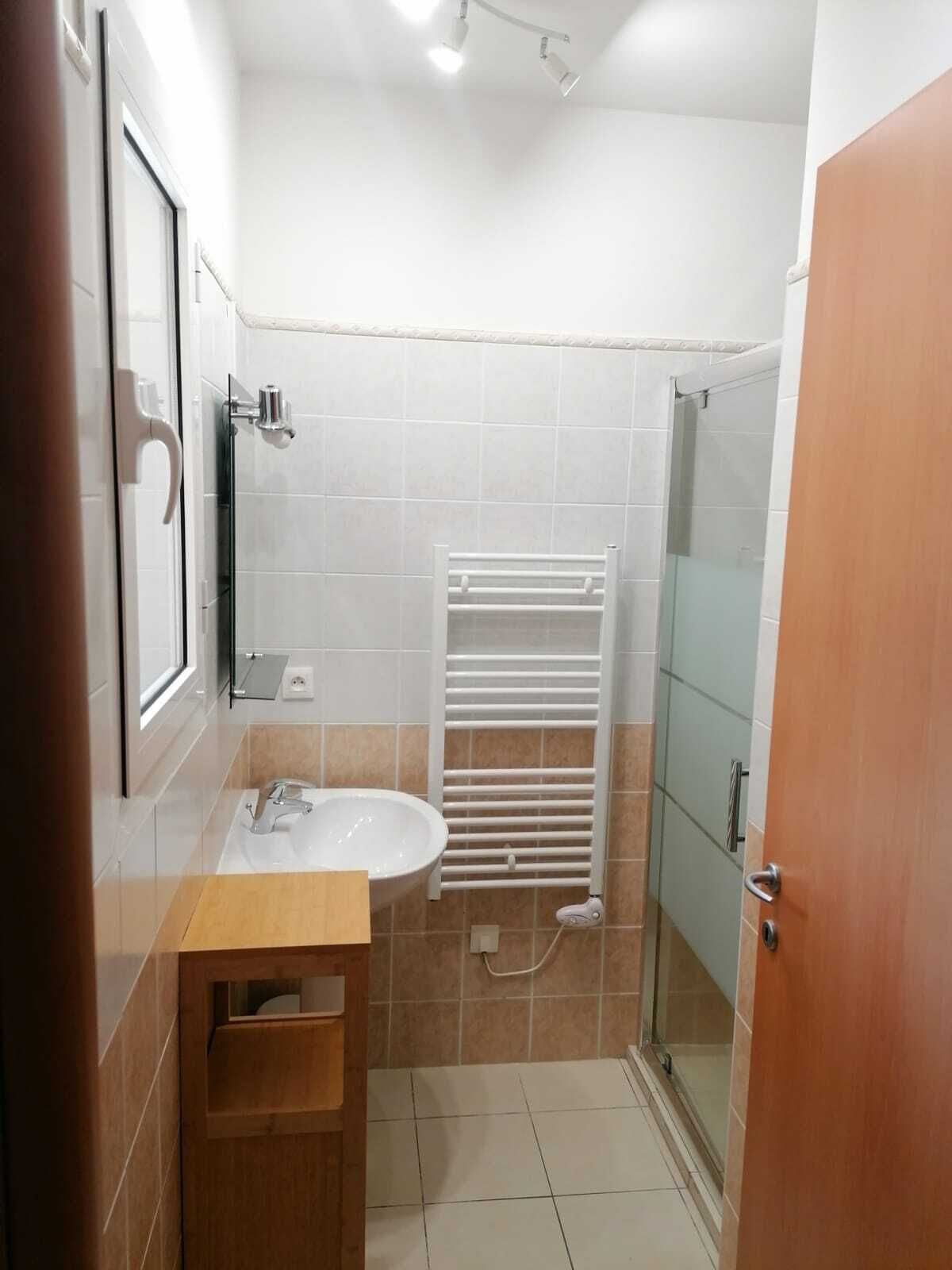 A bathroom with a sink, mirror, towel rack, and a glass shower enclosure.
