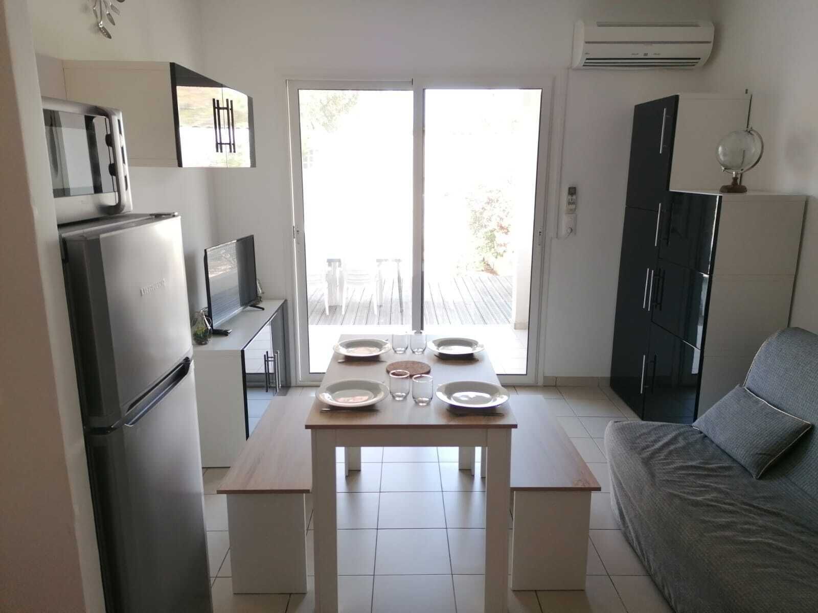 A compact kitchen with a dining table set for four, a sofa, and a TV.
