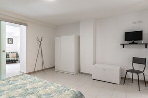 A bedroom with a bed, wardrobe, chair, and a TV on a stand. - Dinologo Modern Flat by Wonderful Italy (Syracuse)