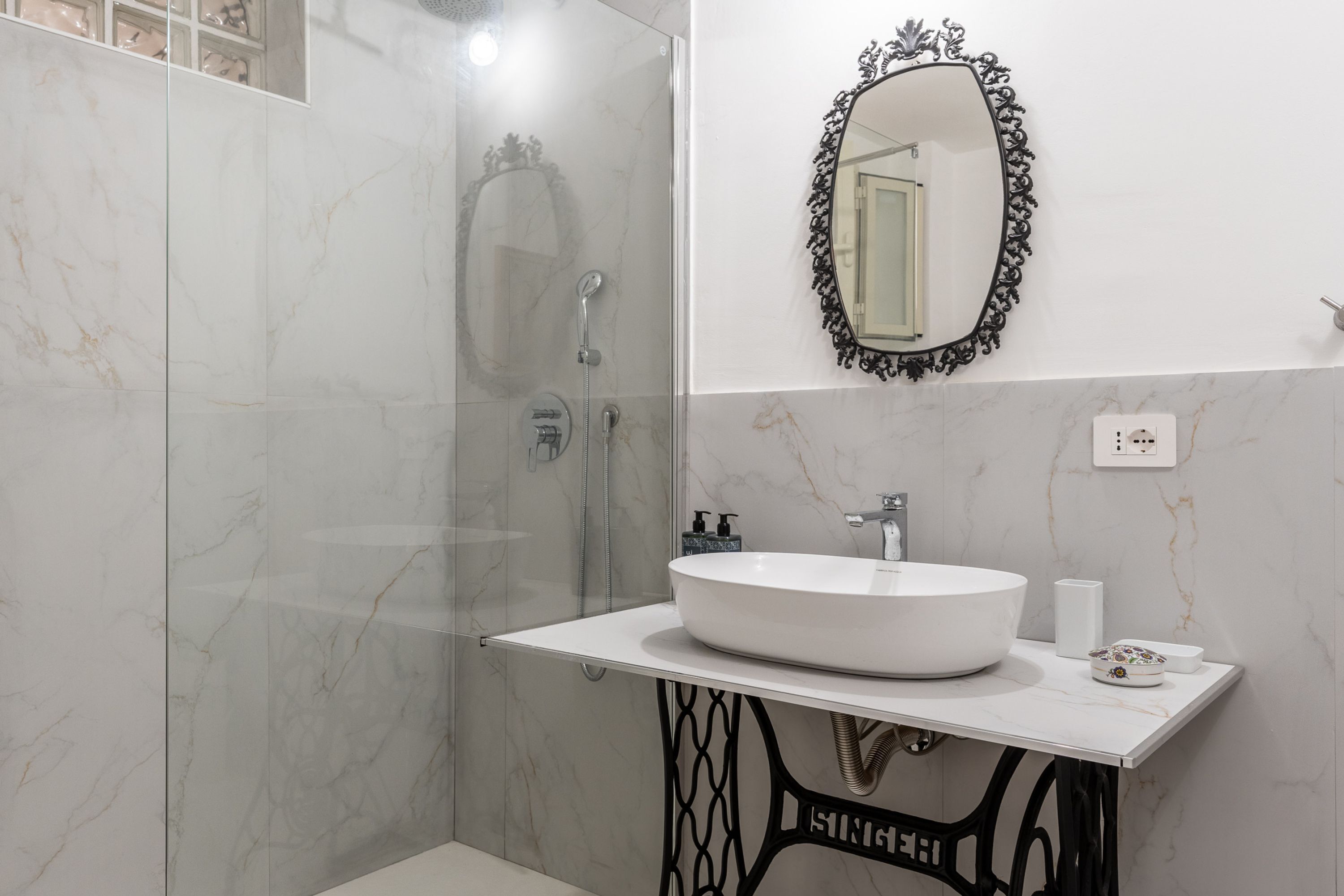 Een badkamer met een wit wastafelmeubel, een spiegel en een douche.