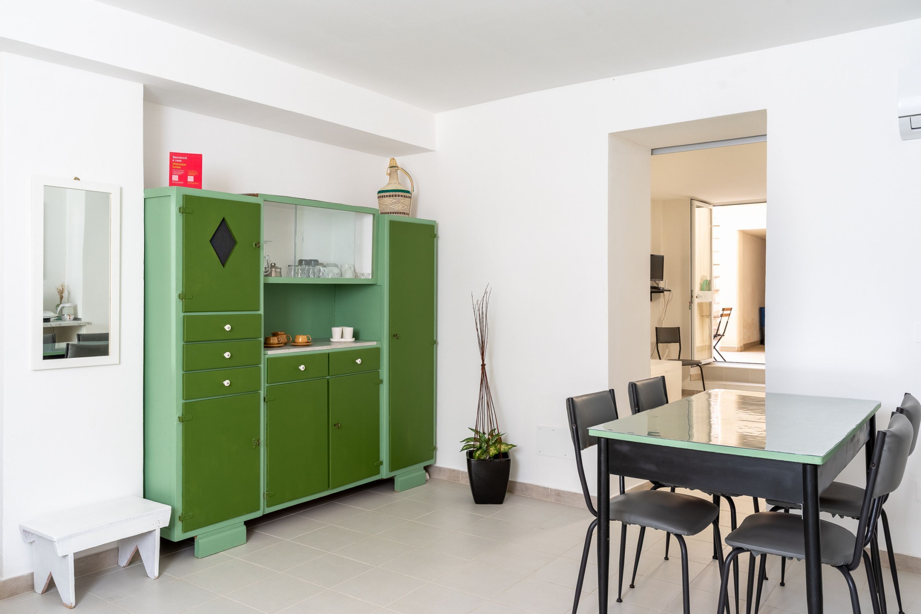Un coin repas avec un meuble vert, une table, des chaises et une plante en pot.