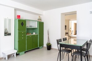 A dining area with a green cabinet, a table, chairs, and a potted plant. - Dinologo Modern Flat by Wonderful Italy (Syracuse)