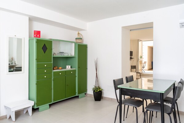A dining area with a green cabinet, a table, chairs, and a potted plant. - Dinologo Modern Flat by Wonderful Italy (Syracuse)