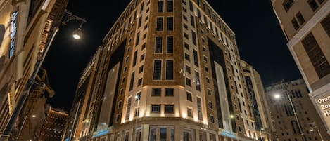 Un hôtel à plusieurs étages, doté d’une entrée d’angle remarquable, de grandes fenêtres et d’une façade bien éclairée.