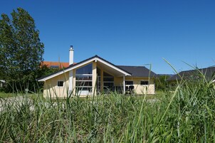 A single-story house with a gabled roof, large windows, and a chimney.