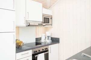 A modern kitchen with white cabinets, a stainless steel microwave, a Bosch coffee maker, and a gas stove.