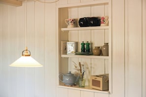 A shelf with various items including a teapot, vases, and a radio. - Half-timbered cottage near Knuthenborg Park (Maribo)