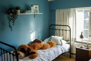 A bedroom with a single bed, a bedside lamp, a radiator, and a window with curtains.