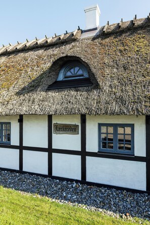 A traditional building with a thatched roof, a sign reading 'Larkereder', and a window with a grid pattern. - Half-timbered cottage near Knuthenborg Park (Maribo)