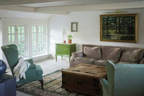 A living room with a green armchair, a brown sofa, a wooden coffee table, and a green cabinet.