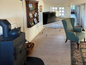 A living room with a fireplace, a television on a stand, a chair, and a bookshelf with books and pictures.