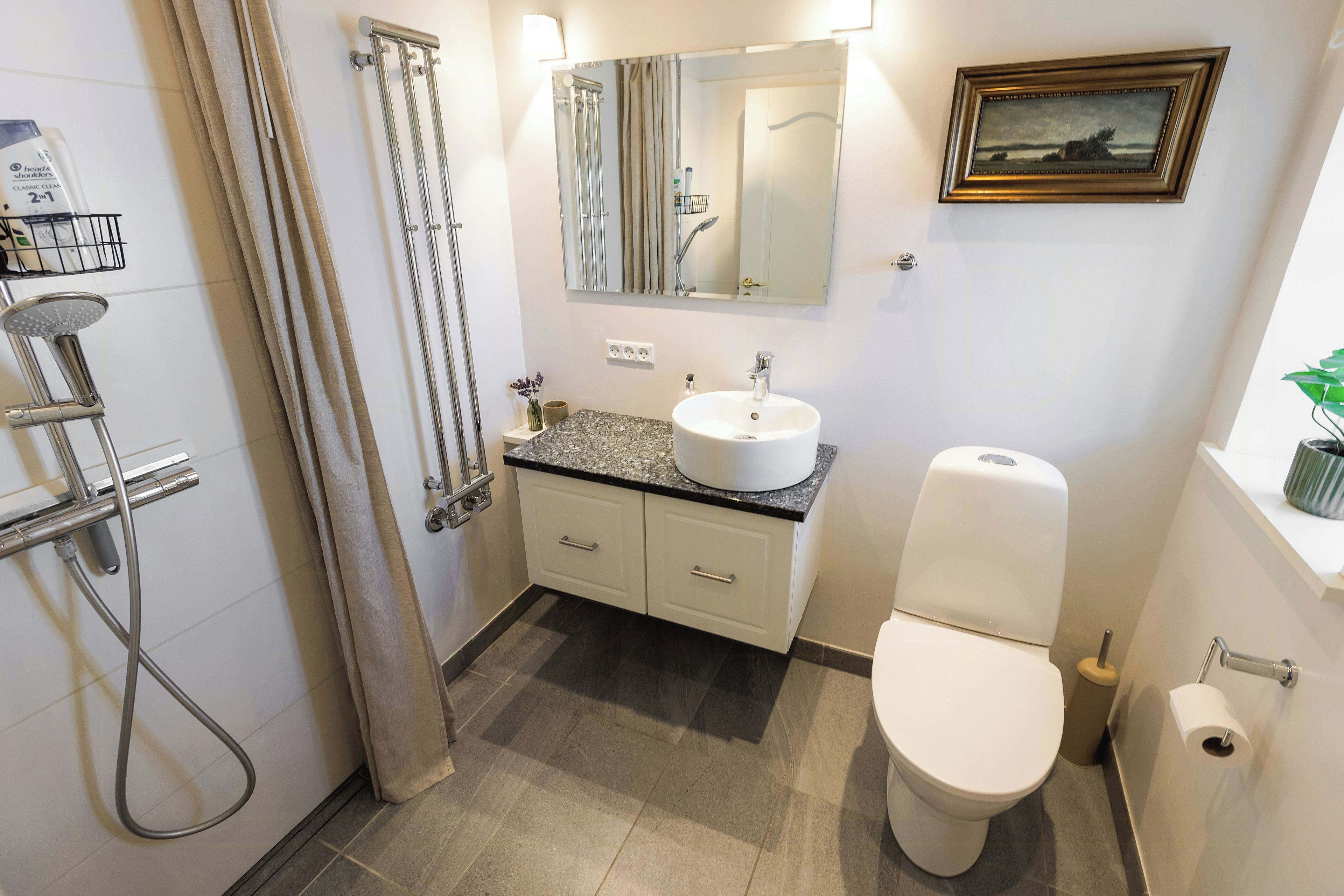 Ein Badezimmer mit Dusche, Toilette, Waschbecken und Spiegel.