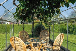 A greenhouse with a glass table and wicker chairs, surrounded by greenery. - Half-timbered cottage near Knuthenborg Park (Maribo)