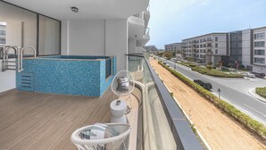 Un balcone con piscina, una sedia e vista su una strada e degli edifici.