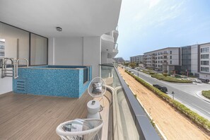 Ein Balkon mit Pool, einem Stuhl und Blick auf eine Straße sowie Gebäude.