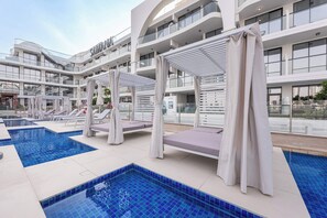 Un hôtel moderne doté d’une piscine sur le toit, avec des chaises longues et un espace salon couvert.