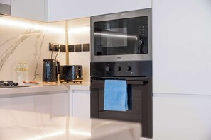 Eine moderne Küche mit integriertem Mikrowellenherd und Backofen, einer Marmor-Spritzschutzwand und einer Edelstahl-Arbeitsplatte.