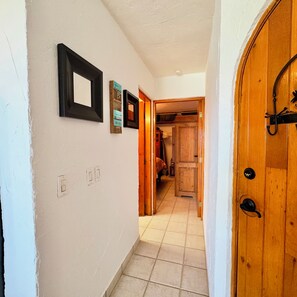 A hallway with a wooden door, a tiled floor, and a wall with framed pictures. - Casa Hayley - 1 bedroom in Cabo San Lucas with arch views, heated pool & AC (Cabo San Lucas)