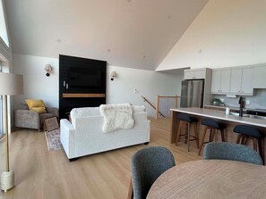A modern living space with a sofa, a dining table, and a kitchen area.