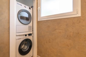 A stacked washer and dryer unit in a room with a window. - Villa Vista Verde - Luxurious Hideaway max privacy (AN)