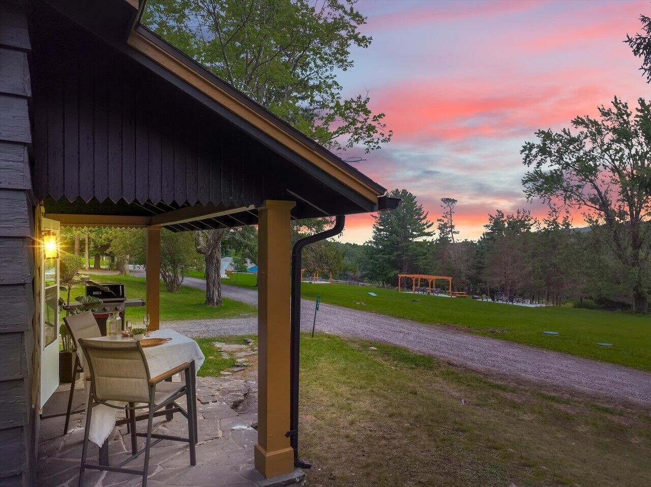 Un espace extérieur abrité, aménagé avec un barbecue, une table et des chaises.