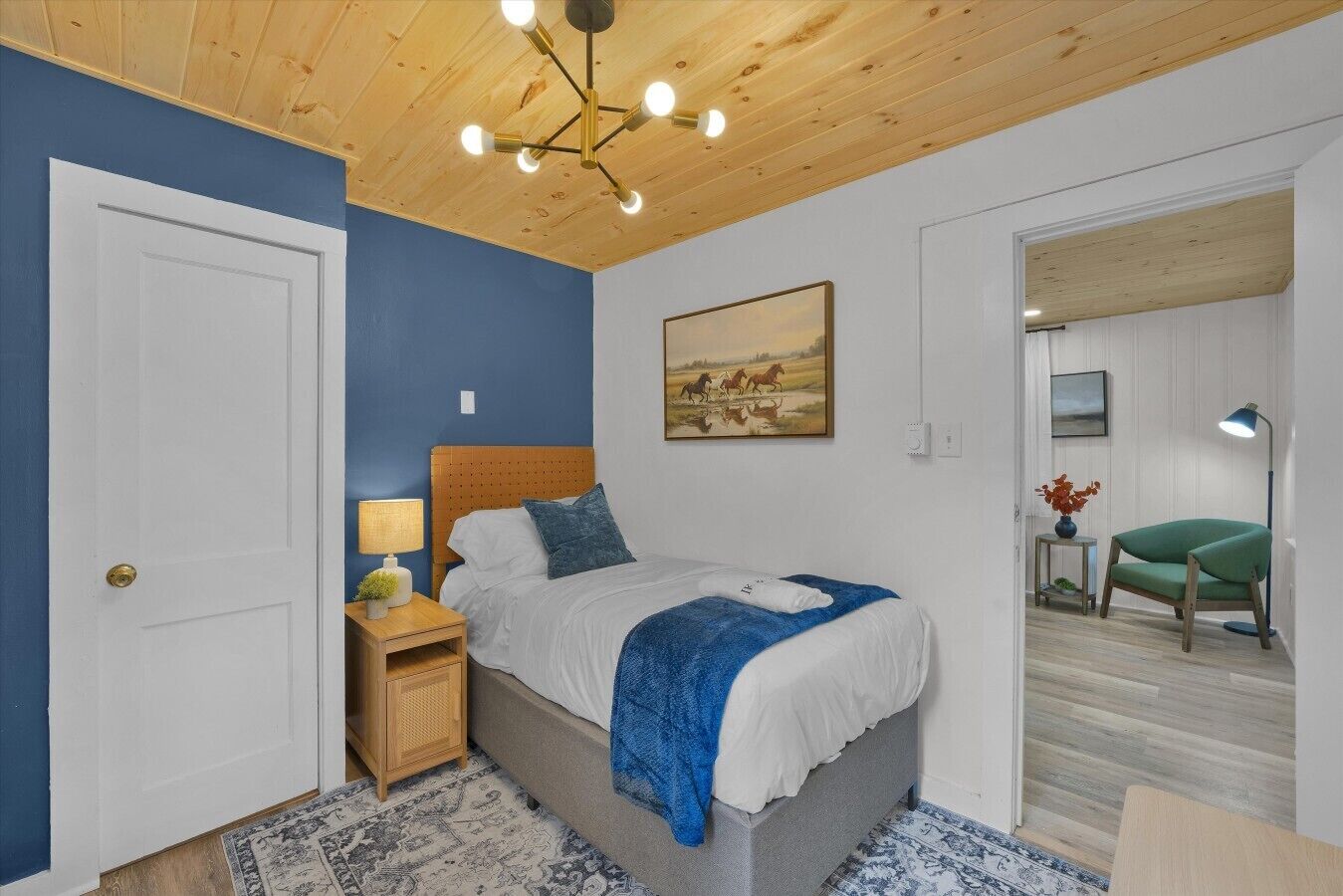 Une chambre à coucher avec un lit, une table de chevet, une lampe, un tableau et une chaise.