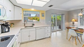 A modern kitchen with a built-in stove, a sink, and a window overlooking a balcony. - 2BR 2BA Updated Beach Apt with Screened Patio (West Palm Beach)