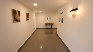 A hallway with a tiled floor, a door, a bench, and wall-mounted artwork. - Villa with Pool · 1 km from the Beach - 30 min from the Airport (Gaio-Rosário)