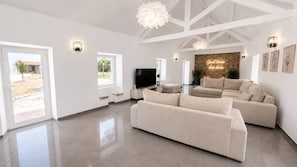 Ein geräumiges Wohnzimmer mit einem großen Ecksofa, einem Flachbildfernseher und einer Wand mit Steinverkleidung.