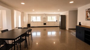 A spacious kitchen with a long dining table, chairs, and a refrigerator. - Villa with Pool · 1 km from the Beach - 30 min from the Airport (Gaio-Rosário)