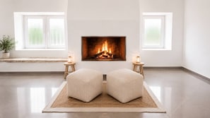 Ein modernes Wohnzimmer mit Kamin, zwei Hocker und einem Teppich.