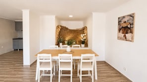 Ein Essbereich mit Steinwand, weißen Stühlen und Holztisch.