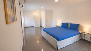 A modern hotel room with a large bed, a bedside table with a lamp, and a wardrobe. - Villa with Pool · 1 km from the Beach - 30 min from the Airport (Gaio-Rosário)