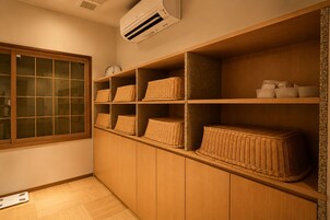 A room with wooden shelving, wicker baskets, a clock, and an air conditioning unit.