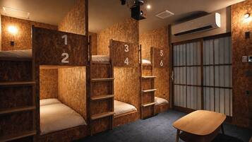 A hotel room with bunk beds numbered 1 to 6, a small table, and a projector on the ceiling.
