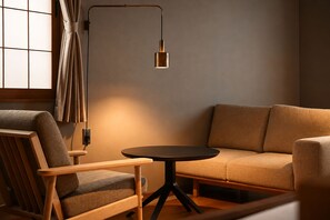 A modern living room with a sofa, a wooden chair, and a small round table.