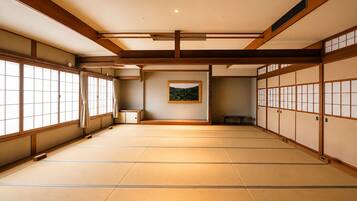 A traditional Japanese room with tatami flooring, sliding doors, and a framed picture on the wall.