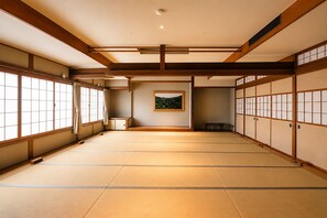 A traditional Japanese room with tatami flooring, sliding doors, and a framed picture on the wall.